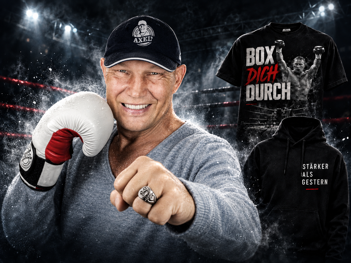 Axel Schulz mit schwarzer Kappe, weißem Boxhandschuh und erhobener Faust neben seinen Fanartikeln